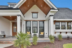 Modern farmhouse exterior with white siding, black trim, wood accents, and inviting front seating.