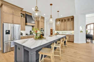 Modern farmhouse kitchen with marble island, wood cabinets, stainless steel appliances, and pendant lighting.