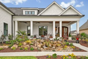 Modern suburban home with white siding, gray shingles, front porch, and landscaped garden.