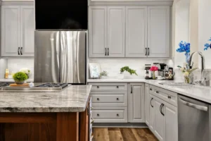 Modern gray kitchen with marble countertops, wooden island, and stainless steel appliances.