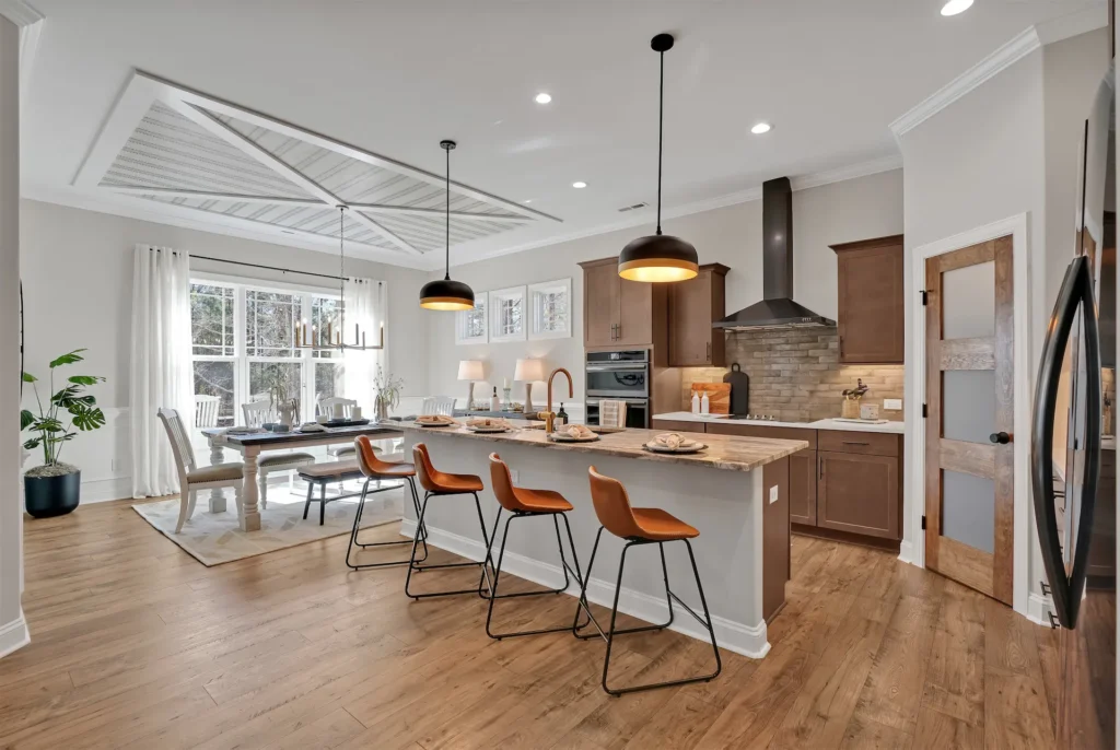 Modern open-concept kitchen with wood cabinetry, stone island, and bright dining area.