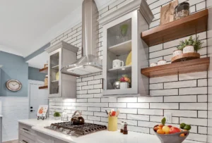 Modern stainless-steel kitchen with white tile backsplash, glass cabinets, and warm wooden accents.