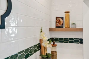 Modern white kitchen with green tile accent, wood shelves, glass jars, and natural decor.