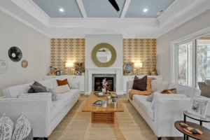 Elegant modern living room with white fireplace, gold accents, and cozy neutral décor.