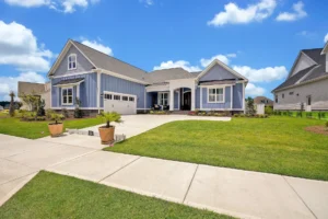 Modern blue suburban house with white trim, two-car garage, and lush green front lawn.