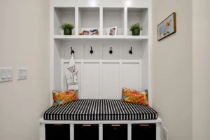 Modern farmhouse mudroom bench with storage, striped cushion, colorful pillows, and decorative cubbies.