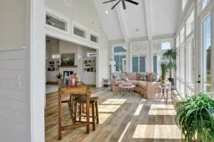 Bright modern farmhouse living room with vaulted ceiling, light wood floors, and natural sunlight.