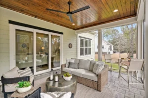 Cozy screened porch with wicker furniture, wood ceiling, and backyard view in Wilmington home.