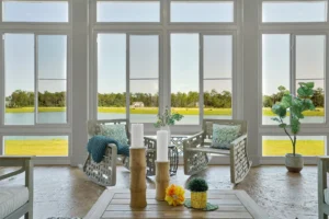 Bright coastal sunroom with wicker chairs, lake view, natural light, and relaxing modern décor.