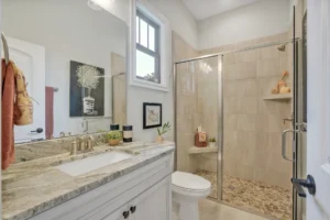 Modern bathroom with granite vanity, glass shower, brushed nickel fixtures, and neutral spa-inspired design.