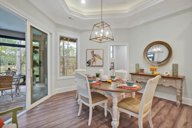 Bright modern dining room with white table, gold light fixture, and natural wood accents.