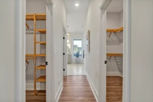 Bright modern hallway with dual walk-in closets, wood shelving, and natural light.