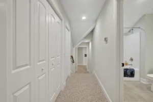 Modern hallway with neutral tones, white doors, beige carpet, and minimalist contemporary design.
