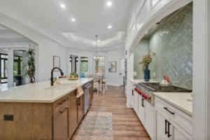 Bright modern farmhouse kitchen with white cabinets, wood island, and green herringbone backsplash.
