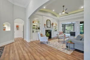 Modern living room with vaulted ceiling, fireplace, wood floors, and elegant neutral décor.