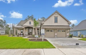 Modern beige farmhouse with metal roof, covered porch, and landscaped yard in Wilmington, North Carolina.