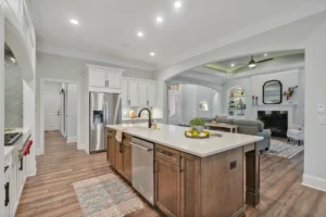 Modern open-concept kitchen with quartz island leading to cozy living room with fireplace.