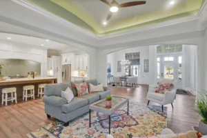 Modern open-concept living room and kitchen with gray sofa, white cabinets, and natural light.
