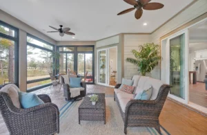 Bright sunroom with wicker furniture, large windows, and natural light overlooking lush greenery.