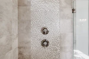 Contemporary gray tile walk-in shower with textured accent wall and chrome fixtures.