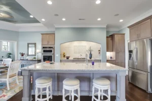 Modern light blue kitchen with quartz island, gray cabinetry, and stainless steel appliances.