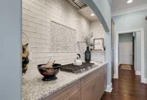 Contemporary kitchen with granite countertops, subway tile backsplash, gas cooktop, and warm wood cabinetry.