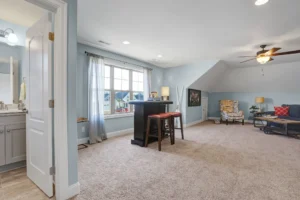 Bright open-concept living room with blue walls, beige carpet, and cozy modern decor.