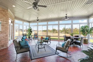 Bright sunroom with modern seating, natural light, tile flooring, and scenic outdoor views.
