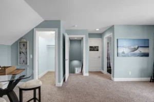 Bright modern attic room with blue-gray walls, beige carpet, and coastal decor.