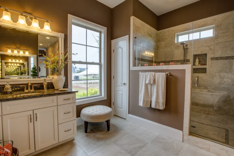 Modern master bathroom with granite vanity, glass shower, and warm natural lighting.
