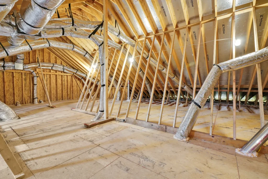 Unfinished attic with exposed wood framing, insulated HVAC ducts, and potential for storage or living space.