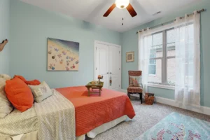 Coastal bedroom with light blue walls, coral accents, and airy beach-inspired décor.