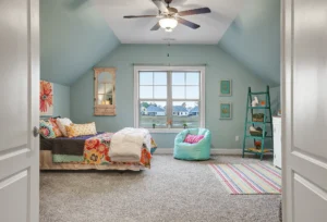 Cozy light blue attic bedroom with colorful bedding, mint-green bean bag, and natural light.