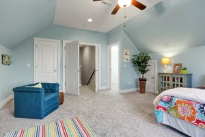 Cozy attic bedroom with soft blue walls, floral bedding, and warm, inviting decor.