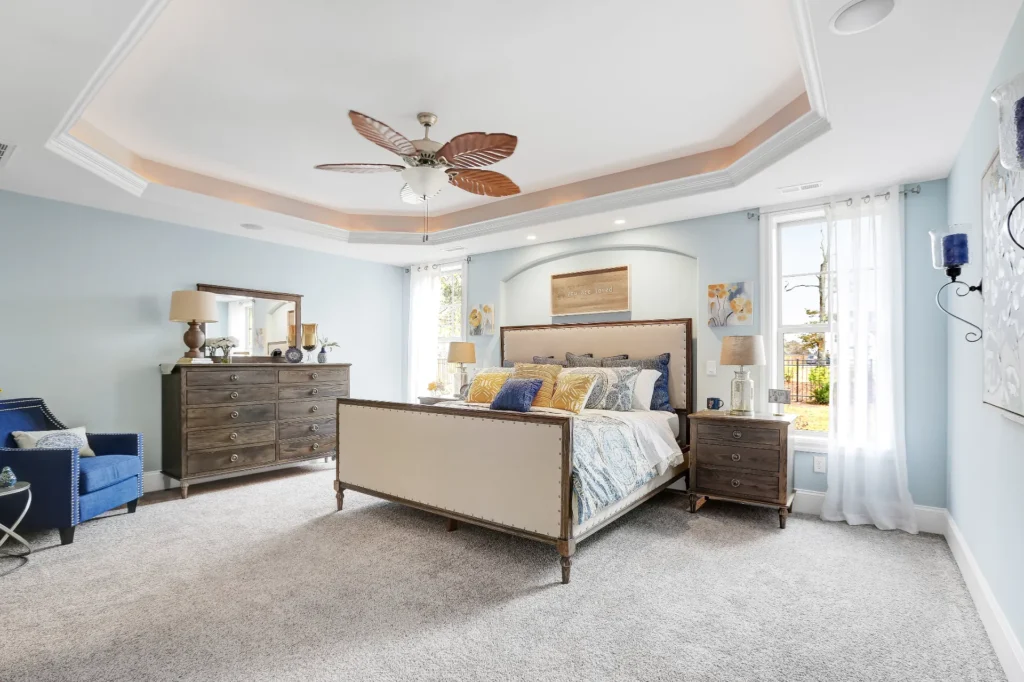 Elegant coastal bedroom with blue and gold accents, wooden furniture, and soft natural lighting.