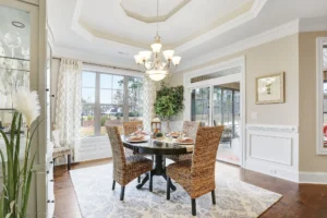 Bright elegant dining room with rattan chairs, round wood table, and abundant natural light.