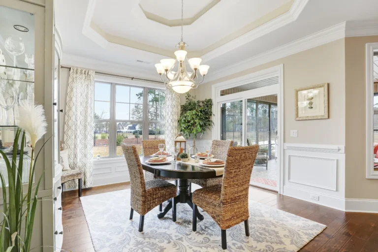 Bright elegant dining room with rattan chairs, round wood table, and abundant natural light.