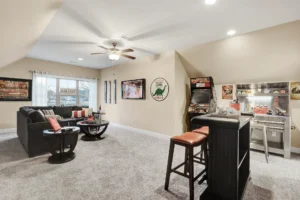 Cozy home game room with sectional sofa, bar, and arcade machine under warm lighting.
