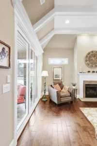 Cozy living room with fireplace, gray armchair, and natural light through large sliding doors.