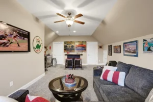 Cozy attic media room with gray sofa, warm lighting, and sports-themed décor.