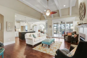 Bright coastal open-concept living room with vaulted ceilings, turquoise accents, and sunlit modern kitchen.
