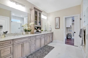 Elegant bathroom with marble vanity, light wood cabinets, and view into adjoining laundry room.