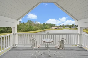 Peaceful lakefront covered porch with white chairs and scenic waterfront view in sunny Wilmington.