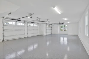 Bright modern three-car garage with polished concrete floor, white walls, and large windowed doors.