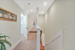 Modern mint-green hallway with staircase, white trim, recessed lighting, and stylish home decor.