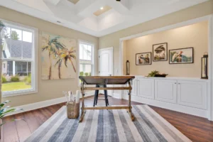 Bright coastal home office with natural light, wooden desk, blue rug, and beach-inspired decor.