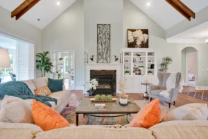Spacious modern rustic living room with vaulted wood-beam ceilings, cozy fireplace, and natural light.