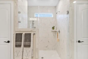 Modern marble walk-in shower with glass enclosure and elegant spa-inspired bathroom design.