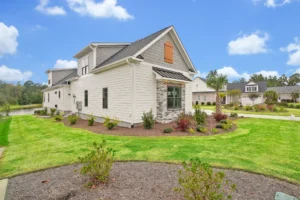 Modern suburban house with stone accents, green lawn, and blue sky in a peaceful neighborhood.