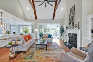 Modern open-concept living room with fireplace, vaulted ceilings, and bright kitchen in elegant design.